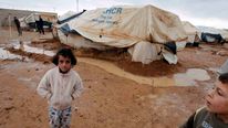 Syrian refugees stand outside their tents after heavy rain at the Al-Zaatari refugee camp in the Jordanian city of Mafraq