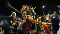 People stand on a Turkish army tank in Ankara