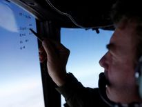 Squadron leader Brett McKenzie marks the name of another search aircraft in the search for the plane
