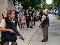 Police officers escort people from inside the shopping centre