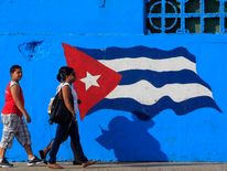 People walk beside a Cuban flag painted on a wall in Matanzas in central Cuba