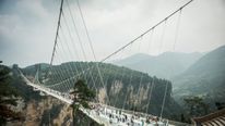 Visitors cross the world's highest and longest glass-bottomed bridge above a valley in Zhangjiajie in China's Hunan Province