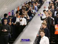 Mayor of London Sadiq Khan (left) and travellers go down the escalators at Brixton Underground station