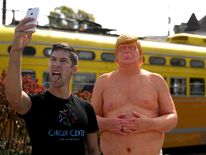 A passerby takes a selfie with a statue depicting republican presidential nominee Donald Trump in San Francisco