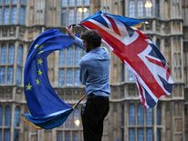 A man waves both a Union flag and a European flag together on College Green outside The Houses of Parliament at an anti-Brexit protest in central London