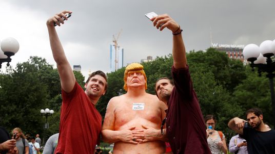 People pose for selfies with a naked statue of U.S. Republican presidential nominee Donald Trump that was left in Union Square Park, New York City
