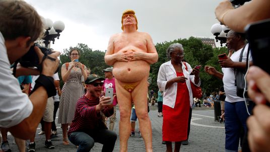 People photograph and pose for selfies with a naked statue of U.S. Republican presidential nominee Donald Trump that was left in Union Square Park, New York City