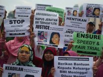 Indonesian migrant workers hold up placards of slain colleagues Seneng Mujiasih and Sumarti Ningsih