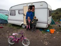 Iraqi migrants Ibrahim, his wife Ashty, their children Mandy (L) and Muhammad (R) pose outside their caravan in the "New Jungle" make-shift camp as unseasonably cool temperatures arrive in Calais, northern France, October 15, 2015. More than 3,500 people, migrants and refugees are camped in Calais, fleeing war and poverty in the Middle East, Africa and Asia and now living in the jungle. Most of them are hoping to make the crossing to England. REUTERS/Philippe Wojazer TPX IMAGES OF THE DAY