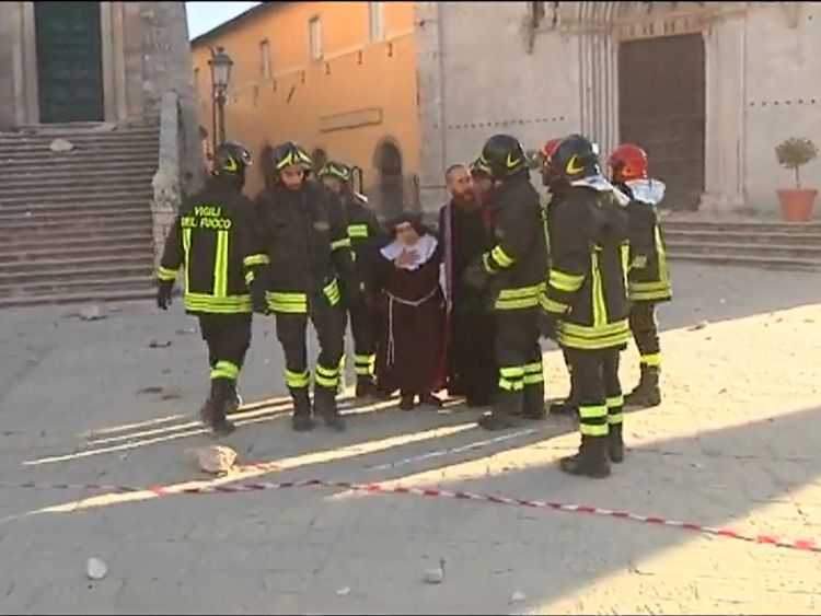 Rescue workers help a nun in Piazza San Benedetto in Norcia