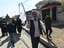Residents wave a white flag as they walk through liberated Gogjali