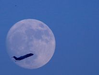 A plane flies past the moon a day before the "supermoon" spectacle in Kathmandu, Nepal November 13, 2016