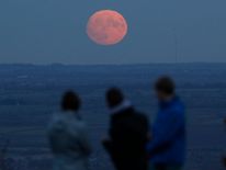 A family watch the moon rise a day before the "supermoon" spectacle on Beacon Hill near Loughborough, Britain, November 13, 2016