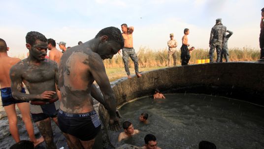 Iraqi soldiers, youths and police enjoy the muddy spring water following the recapture of Hammam al-Alil from IS 