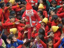 A boy dressed as Santa is mobbed by his classmates as he gives out sweets in Amritsar, India