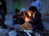 Syrians evacuated from eastern Aleppo, light a fire using plastic bags to keep warm, inside a shelter in government controlled Jibreen area in Aleppo, Syria November 30, 2016. REUTERS/Omar Sanadiki