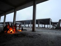 Syrians evacuated from eastern Aleppo keep warm by a fire, under a shelter in government controlled Jibreen area in Aleppo, Syria November 30, 2016. REUTERS/Omar Sanadiki