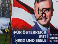 A vandalised poster of Norbert Hofer is seen next to a poster of rival Alexander Van der Bellen