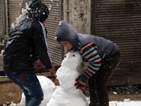 Syrian children make a snow man in the town of Maaret al-Numan, in Syria's northern province of Idlib, on December 21, 2016. Rebels and civilians who have sought refuge in the opposition-held province of Idlib, most recently from second city Aleppo, say they are suffering from skyrocketing prices and overpopulation. At least 25,000 people, including rebel fighters, have left east Aleppo since last week under an evacuation deal that will see the city come under full government control