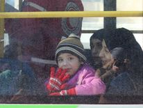 A child waves from inside a bus as she is evacuated from rebel-held areas in Aleppo