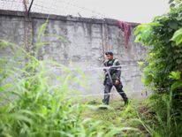 An armed policeman patrols along the perimeter fence of the district jail