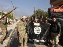 Members of the Iraqi rapid response forces stand with an Islamic State flag which they pulled down during a battle between Iraqi forces and Islamic State militants in the Wahda district of eastern Mosul, Iraq, January 8, 2017