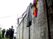 Armed police patrol along the perimeter fence of the district jail