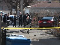 Police look over the bullet-riddled car