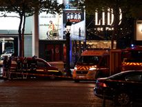 Firefighters and rescuers stand by the site of a shooting on the Champs Elysees in Paris