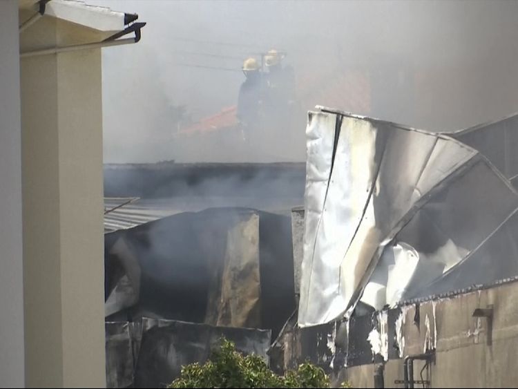 Firefighters can be seen through the smoke surrounded by metal from the building