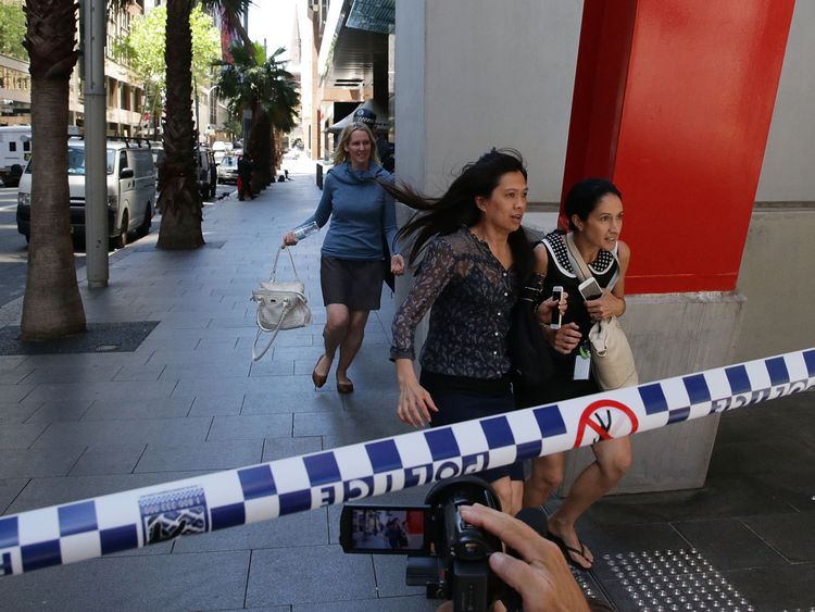 Ladies rush through Philip St past armed police at Lindt Cafe, Martin Place on December 15, 2014