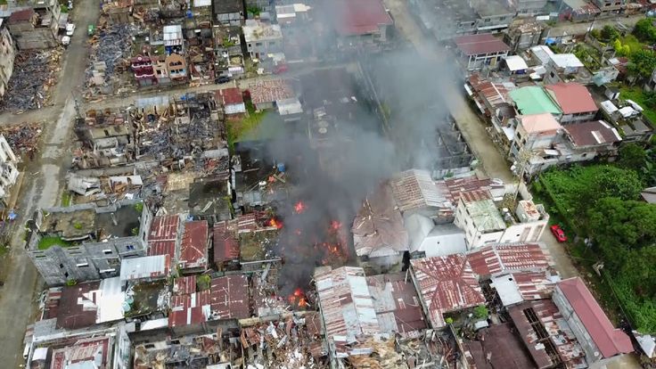 Streets around a mosque have been flattened and large fires burn in the ruins