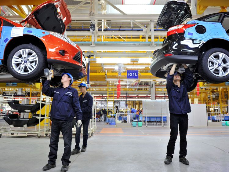 Employees install car components at an assembly line at a Ford manufacturing plant in China