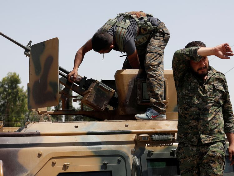 A Kurdish fighter from the YPG adjusts a gun on an armoured vehicle in Raqqa