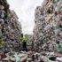 A recycling plant employee in London sweeps from inside a stack of plastic bottles