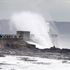 Waves crash over the lighthouse at Porthcawl in Wales