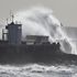 Waves crash over the lighthouse at Porthcawl, South Wales