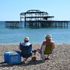 People sunbathe on the beach near the derelict West Pier in Brighton