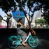 A woman cycles past a screen showing a news conference in Beijing