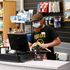 An employee wearing a protective face mask serves a customers at Willen Hospice charity shop