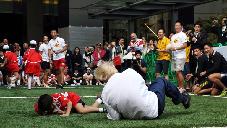 London Mayor Boris Johnson (right) and a school boy collide as they play rugby in Tokyo