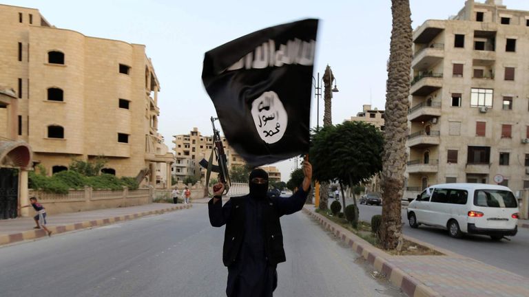 A member loyal to the ISIL waves an ISIL flag in Raqqa, Syria