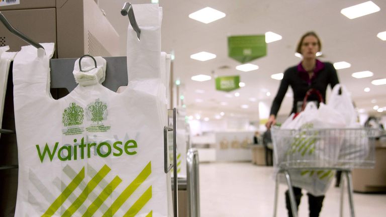 A shopper passes by branded bags in the Canary Wharf store of Waitrose in London.