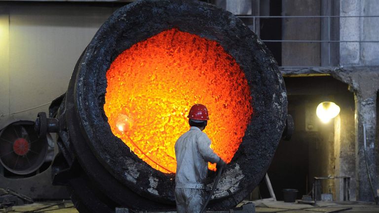 A worker stokes a giant cauldron at a steel mill in China