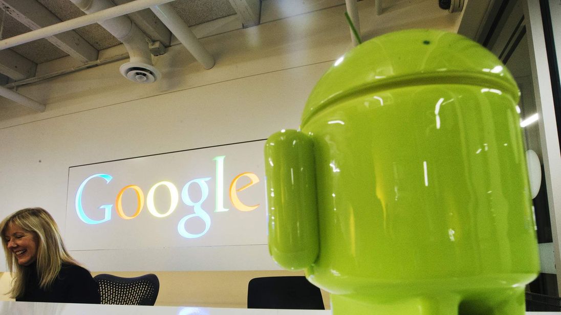 A Google Android figurine sits on the welcome desk as employee McNeilly smiles at the new Google office in Toronto