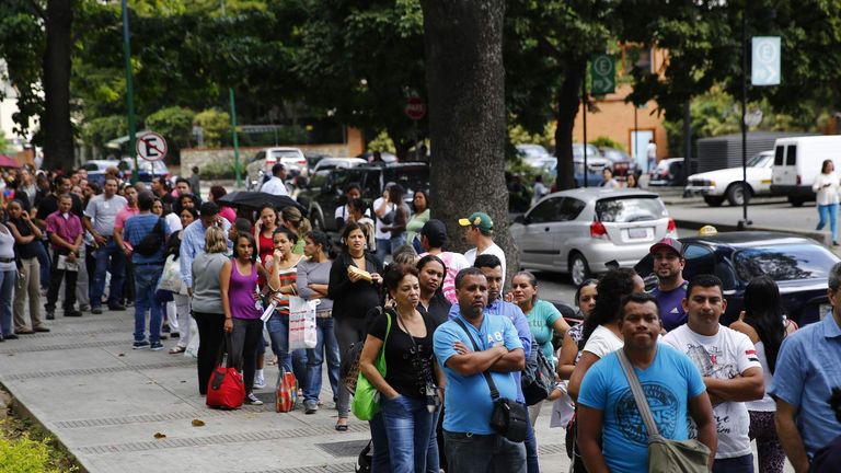 People line up outside a pharmacy to buy baby diapers in Caracas