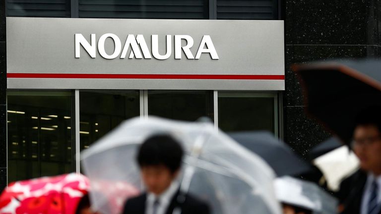 People walk past a branch of the Nomura financial services group in Tokyo