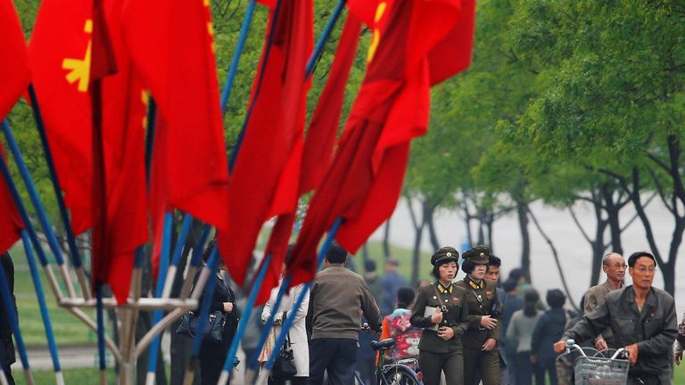 People walk behind party flags placed near the April 25 House of Culture, venue of the Workers' Party of Korea (WPK) congress in Pyongyang, North Korea