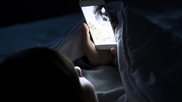 Woman using phone in bed