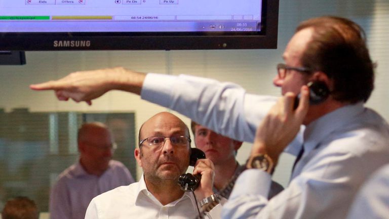 Traders from BGC, a global brokerage company in London's Canary Wharf financial centre react during trading